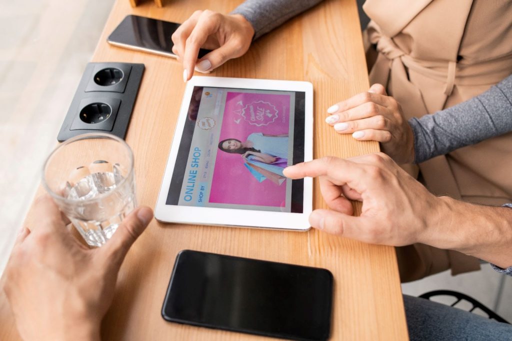 An iPad resting on a table with hands hovering over it,
